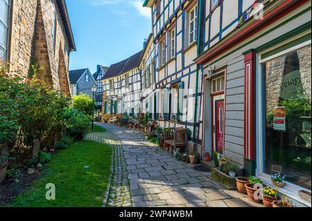 Blick auf eine gepflasterte Gasse mit Pflanztöpfen entlang der alten Fachwerkhäuser, Altstadt, Hattingen, Ennepe-Ruhr-Viertel, Ruhrgebiet, Nord Stockfoto