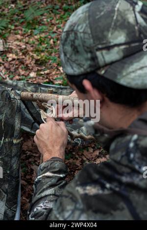 Vertikales Porträt von hinten in diesem fesselnden Bild sieht man einen Entdecker, der Holzstangen zusammenbindet, um seinen Unterschlupf inmitten des riesigen Ex zu konstruieren Stockfoto