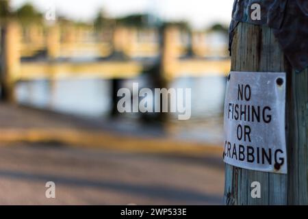 Ein Schild an einem Holzpfahl im Sandy Point State Park, das Angeln und Krabbenfischen verbietet. Stockfoto