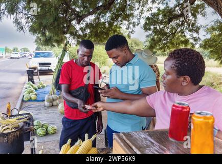 afrikanischer Straßenverkäufer, der Mais und Wassermelonen am Straßenrand verkauft Stockfoto