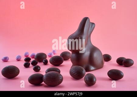 Osterkomposition mit Schokoladenei und Häschen auf rosa Hintergrund. Stockfoto