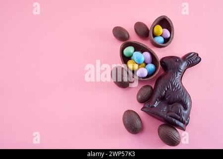 Osterkomposition mit Schokoladenei und Häschen auf rosa Hintergrund. Stockfoto