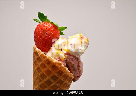 Köstliches Eis mit Vanille und Beeren in einem Waffelkegel mit frischem Erdbeeren- und Minzblatt auf weißem Hintergrund Stockfoto