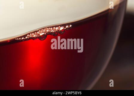 ROTWEINGLAS CLOSE-UP belüftete belüftete Weinoberflächenblasen. Verkostung von feinem Rotwein mit Belüftung. Aus nächster Nähe sehen Sie die Blasen, die sich in einem frisch gegossenen Glas Rotwein bilden. Stockfoto