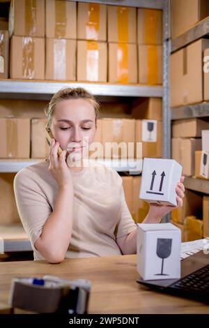 Frau, die ein Mobiltelefon oder Tablet verwendet, um mit Kunden zu kommunizieren. Lieferung von Waren über private Kurierdienste. Konzepte des Online-Verkaufs und weiter Stockfoto