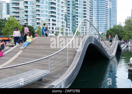 Touristen und Fußgänger versuchen, auf dem Simcoe Wave Deck zu laufen, einem fantasievollen Beispiel urbaner Kunst am Harbourfront in der Innenstadt von Toronto, Ontario. Stockfoto