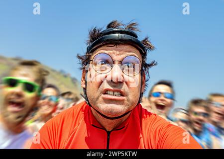 Ein Radfahrer in einem Retro-Helm fährt durch einen Flur jubelnder Zuschauer Stockfoto