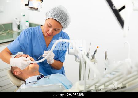 Ärztin behandelt die Zähne des Patienten mit einer Bor-Maschine in der Klinik Stockfoto