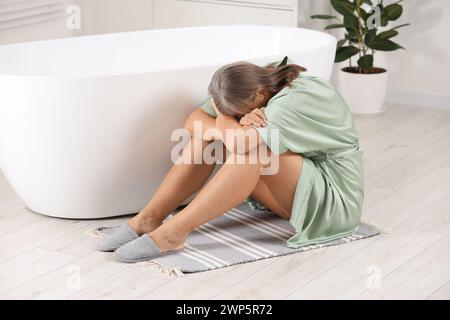 Wechseljahre. Deprimierte Frau in der Nähe der Badewanne im Badezimmer Stockfoto