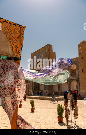 27. JUNI 2023, BUCHARA, USBEKISTAN: Schöne ethnische Stoffe, die mit dem Wind wehen, neben der alten Madrasah, Buchara, Usbekistan. Selektiver Fokus mit Stockfoto