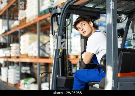 Ein junger Arbeiter arbeitet am Lader im Lager Stockfoto