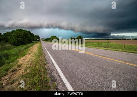 Eine leere Straße führt zu einem schweren Gewitter mit einer niedrigen Schelfeile und starkem Regen. Stockfoto