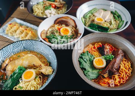 Auf einem Tisch werden verschiedene asiatische Gerichte serviert, darunter Schüsseln mit Ramen, Nudeln und Fleisch. Die Präsentation ist bunt und appetitlich, mit einem M Stockfoto