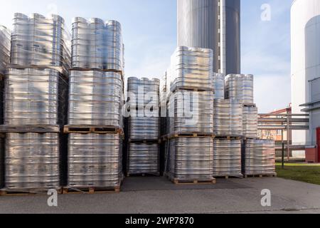 Große Menge an Aluminium-Bierfässern, die mit Euro-Paletten übereinander gestapelt und mit Vinylfolie umwickelt sind. Das Bier, das zum Versand bereit ist, ist eine Flasche Stockfoto