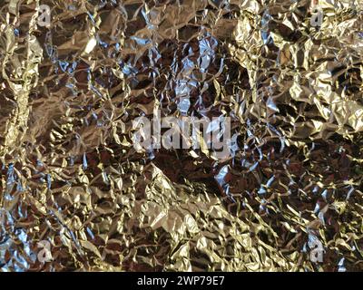 Zerknitterte Aluminiumfolie. Reflexion und Brechung des Lichts in verschiedenen Richtungen. Das Spiel von Licht und Schatten. Stockfoto