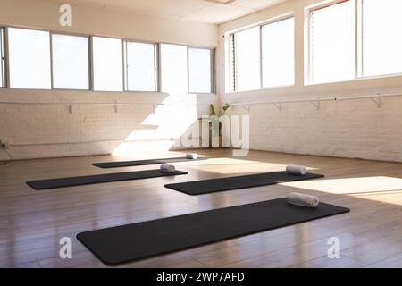 Ein ruhiges Yoga-Studio erwartet die Praktizierenden, in natürliches Licht getaucht, mit Kopierraum Stockfoto