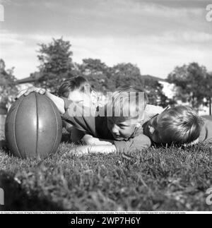 Rugby 1940. Drei junge Rugbyspieler liegen im Gras auf dem Rugbyfeld, einer hält den Rugbyball. Der Rugbyball hat eine ovale Form, vier Panels und ein Gewicht von etwa 400 Gramm. 1942. Kristoffersson Ref. A56-5 Stockfoto