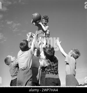 Rugby 1940. Ein junger Rugbyspieler hält den Rugbyball in den Händen, während die anderen Jungs versuchen, ihn zu erreichen. Der Rugbyball hat eine ovale Form, vier Panels und ein Gewicht von etwa 400 Gramm. 1942. Kristoffersson Ref. A55-2 Stockfoto