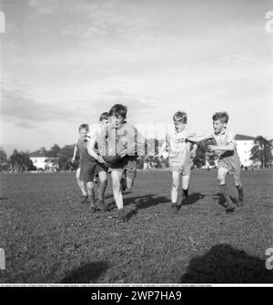 Rugby 1940. Junge Rugbyspieler üben gemeinsam. Der Junge, der mit dem Rugbyball läuft, wird verfolgt. Der Rugbyball hat eine ovale Form, vier Panels und ein Gewicht von etwa 400 Gramm. 1942. Kristoffersson Ref. A56-3 Stockfoto