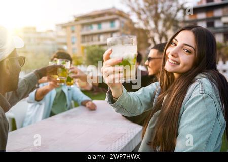 Multirassische Freunde, die bei einem fröhlichen Treffen im Freien Gläser anschlagen, Momente mit frischen Getränken feiern – Konzept der Freundschaft, Vielfalt und Kommunikation Stockfoto