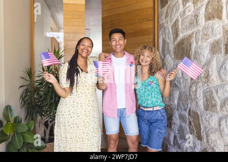 Verschiedene Freunde halten amerikanische Fahnen an einem Hauseingang Stockfoto