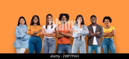 Sieben verschiedene junge Erwachsene mit selbstbewussten Posen und warmem Lächeln stehen hintereinander Stockfoto