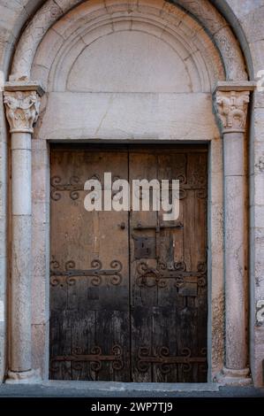 Detail einer alten Holztür mit kunstvollen schmiedeeisernen Scharnieren und Riegel und Bogen und Steinsäulen im französischen Dorf Villefranche de Conflent. Stockfoto