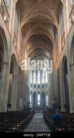 Rocamadour-Kirche in Frankreich vom Hauptschiff aus. Der Altar hat hinten eine sehr hohe Decke und auf den Stühlen sitzt ein Mann. Stockfoto