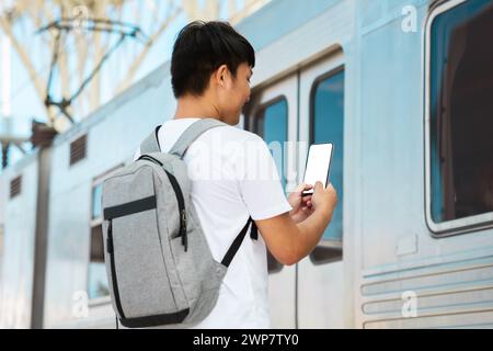 Rückansicht asiatischer Tourist, der sein E-Ticket am Telefon überprüft Stockfoto