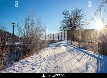 Eine schneebedeckte Straße in einem Dorf an einem Wintermorgen Stockfoto