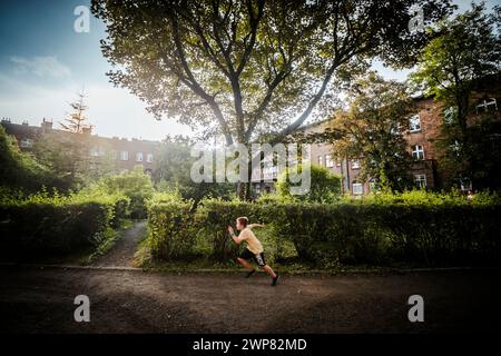 Nikiszowiec, Polen – 14. April 2020: Ein Junge, der durch den grünen Innenhof im Bergbaugebiet Kattowitz, Schlesien, läuft Stockfoto