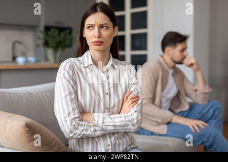 Verärgerte Frau mit überkreuzten Armen, Mann im Hintergrund Stockfoto