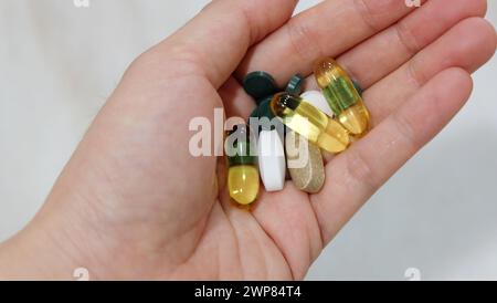 Nahaufnahme der Hand mit verschiedenen Ergänzungspillen und Kapseln. Stockfoto