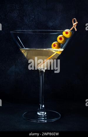 Martini. Ein Glas schmutziger Martini-Cocktail mit Wermut und Oliven, Aperitif, auf dunklem Hintergrund Stockfoto