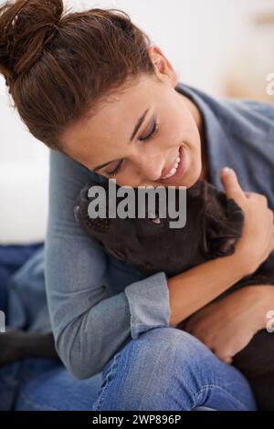 Hund, Frau und Umarmung mit Lächeln für Tier, Haustier und zusammen drinnen für Bindung, Zuneigung und Freundschaft. Hündchen, Dame oder Besitzer zum Lachen und Heim mit Stockfoto