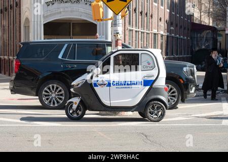 RIESIG WINZIG. Ein großer Cadillac Denali parkte hinter einem kleinen dreirädrigen Chaverim-Minifahrzeug in Williamsburg, Brooklyn, New York. Stockfoto