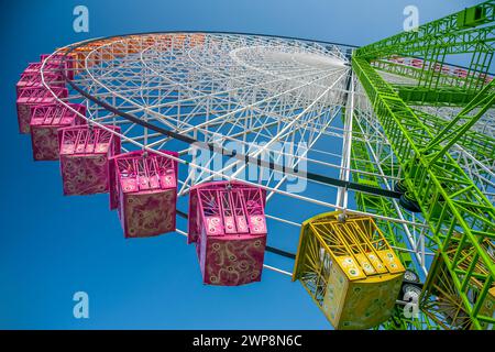 Ein farbenfrohes Riesenrad ragt unter einem klaren blauen Himmel. Stockfoto