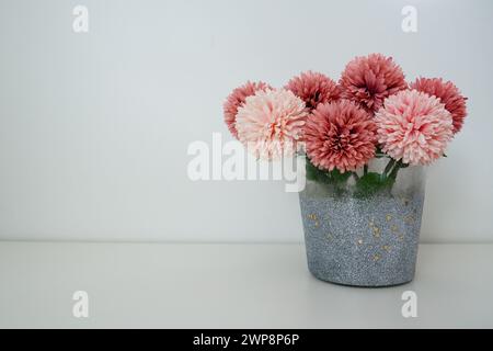 Blumenstrauß aus rosa Frottee-Kunstblumen in einer grauen silbernen Vase auf weißem Hintergrund. Stillleben, Option zur Inneneinrichtung. Zimmereinrichtung. Freier Speicherplatz Stockfoto