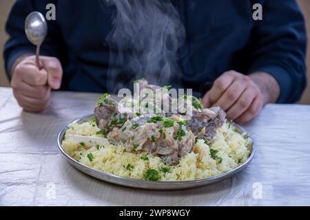 Heißer, frischer Mansaf-Dampf mit den Händen um ihn herum, bereit, auf dem Familientisch für iftar gegessen zu werden Stockfoto