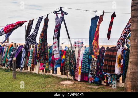 Viele bunte Kleider, Schal und Röcke hängen an der Schnur und fliegen im Wind am Strand. Sri Lanka, Waskaduwa. Stockfoto