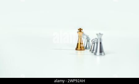 Goldenes Königsschach auf dem Brett vor silbernen Schachstücken auf weißem Hintergrund mit Kopierraum, Führung, Kämpfer, Geschäftsführung, Wettbewerb Stockfoto