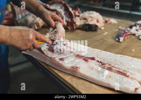 Mann Metzger im Gefrierschrank, der Fleisch schneidet. Schweinefleisch oder Rindfleisch auf dem Tisch in der Metzgerei. Hochwertige Fotos Stockfoto