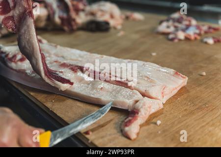 Ein Metzger, der im Schlachthof dünne Schweinefleischscheiben schneidet. Hochwertige Fotos Stockfoto