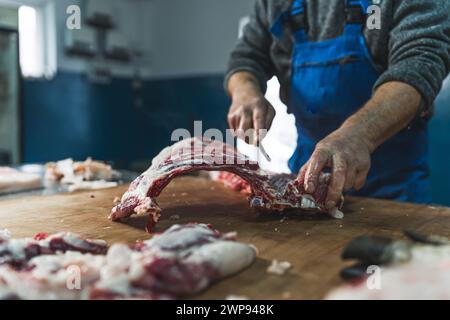 Der Metzger hat rohe Schweinefleisch mit einem Messer am Tisch im Schlachthof geschnitten. Hochwertige Fotos Stockfoto