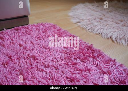 Langer Teppich in Pink auf beigem Laminatboden. Feminine Innenausstattung für ein Zimmer oder Schlafzimmer eines Mädchens oder einer Frau. Inneneinrichtung in rosafarbenen Tönen. Bodenbelag Stockfoto