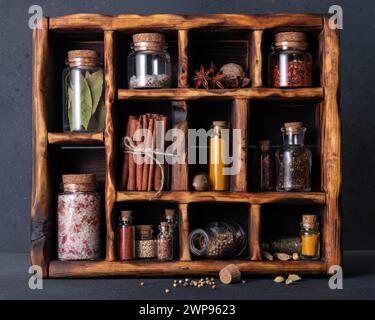 Gewürze (Kräuter und Gewürze) in kleinen Flaschen mit Kork in einer Holzkiste Stockfoto