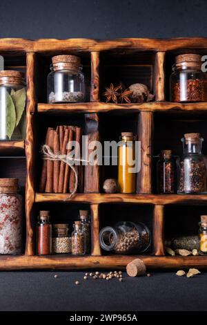 Gewürze (Kräuter und Gewürze) in kleinen Flaschen mit Kork in einer Holzkiste Stockfoto