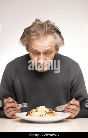 Ein älterer Mann isst Spaghetti mit Hackfleisch, Tomaten und Käse Stockfoto