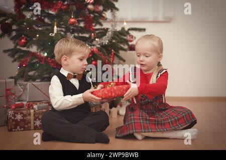 Kinder zum weihnachtsfeiertag packen Geschenke in der Nähe eines Baumes aus Stockfoto