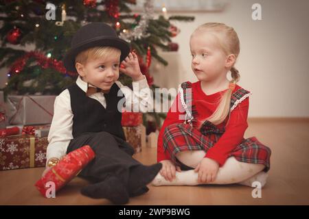 Kinder zum weihnachtsfeiertag packen Geschenke in der Nähe eines Baumes aus Stockfoto